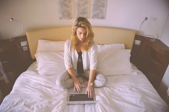 femme assise sur son lit confortable avec un ordinateur portable